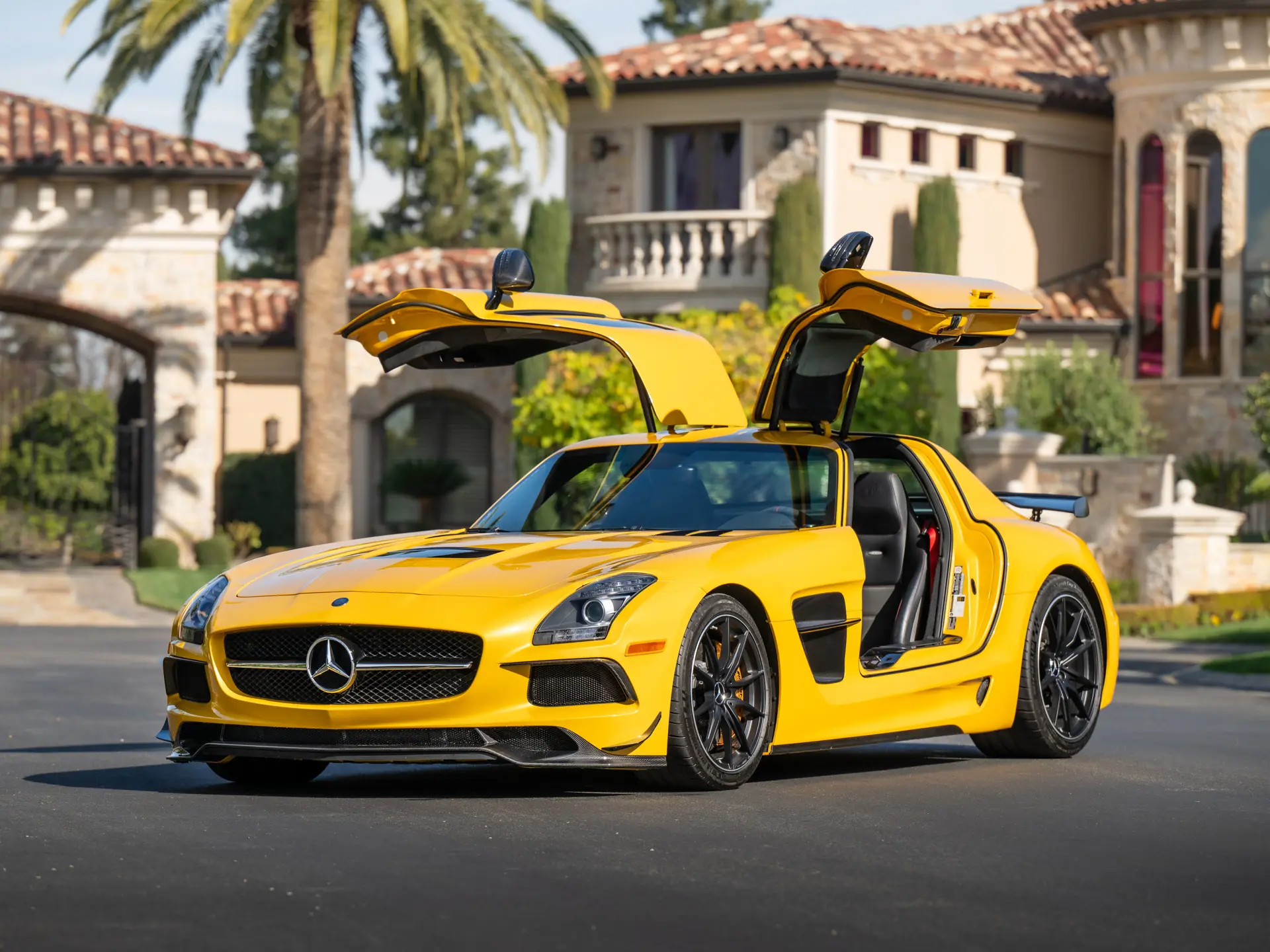 2013 Mercedes-AMG SLS Black Series in Solar Beam Yellow with both gullwing doors raised at a Spanish villa — GT3-inspired carbon aero kit, 631 PS naturally aspirated V8, now selling for up to $940,000 at auction