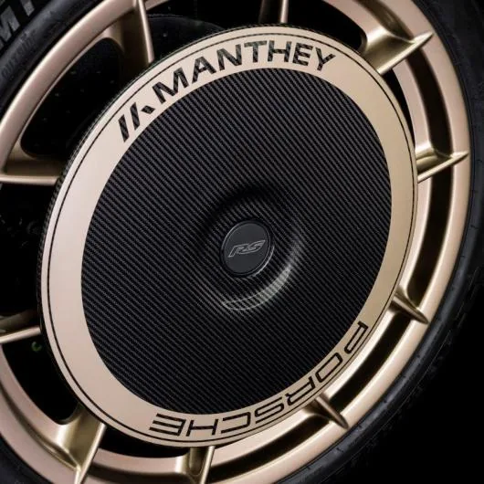 Carbon aero wheel cover with Manthey and Porsche lettering on a gold wheel
