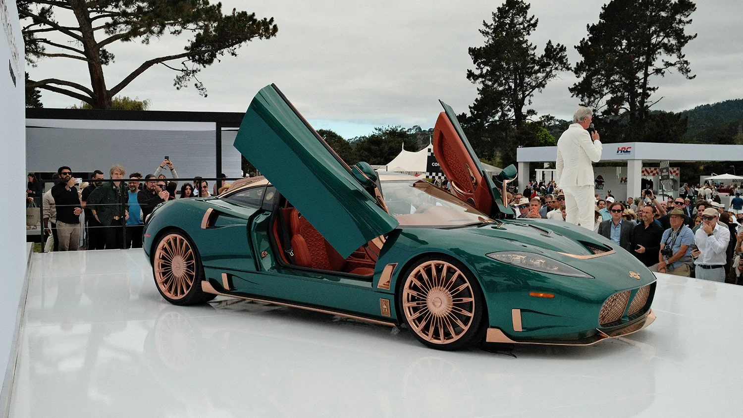 Spyker C8 Preliator XXV debut at The Quail 2026 with scissor doors open and Victor Muller on stage