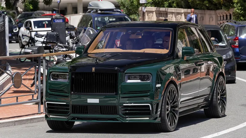Dark green Rolls-Royce Cullinan with Mansory widebody kit and black wheels, front view on a street